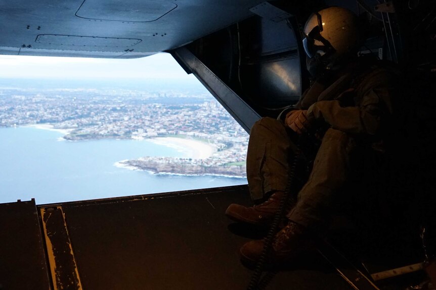 Australian troops look out from a military helicopter across to the Sydney shoreline.