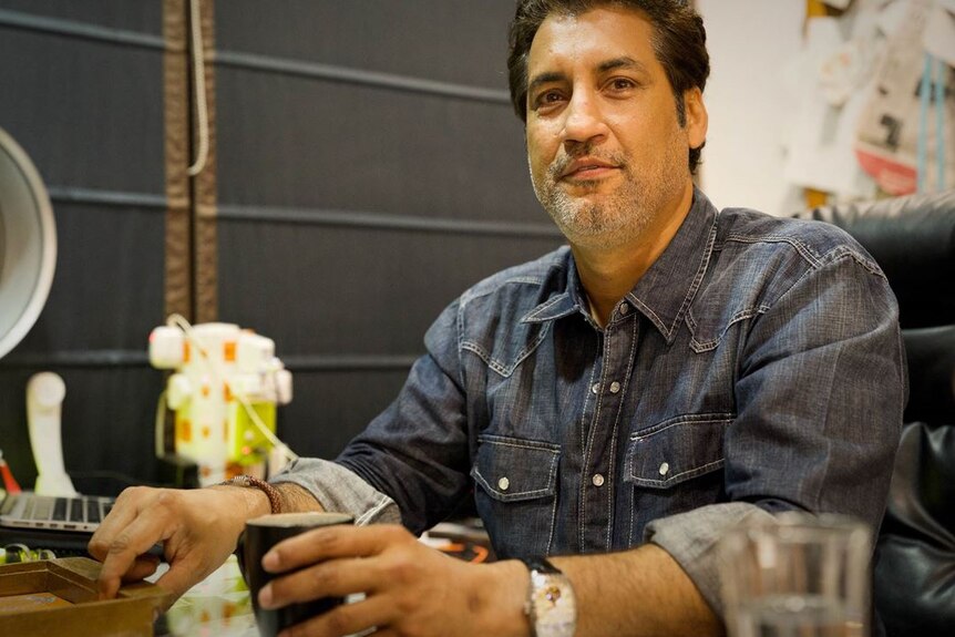 Atul Wassan sits at a table in a cafe with an empty coffee cup in front of him.