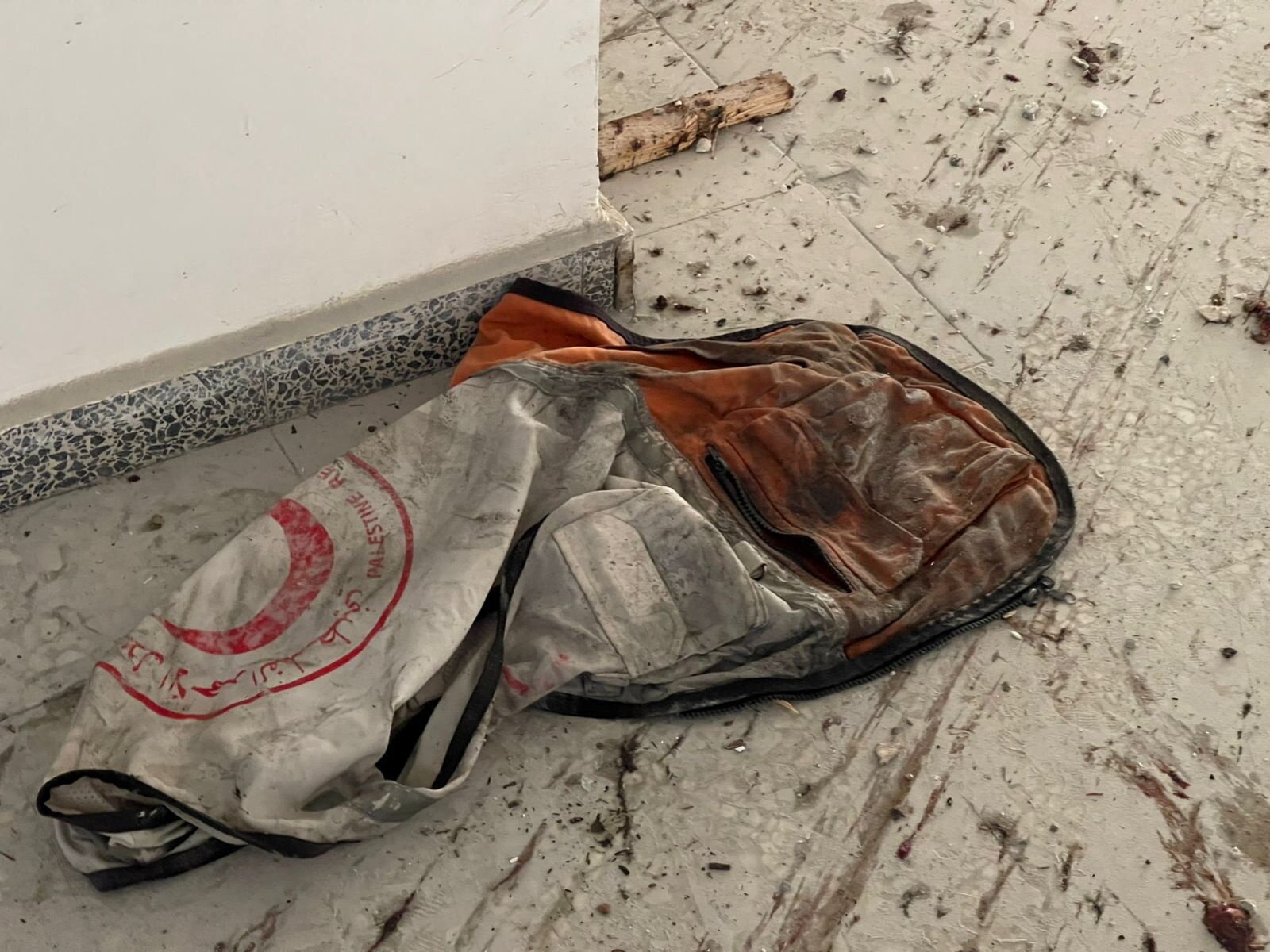 A flag on the ground with the Palestinian Red Crescent logo on it, dirtied by an air strike.
