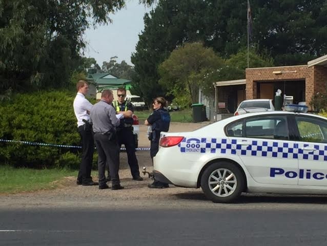 Four people standing near a police car outside a house.