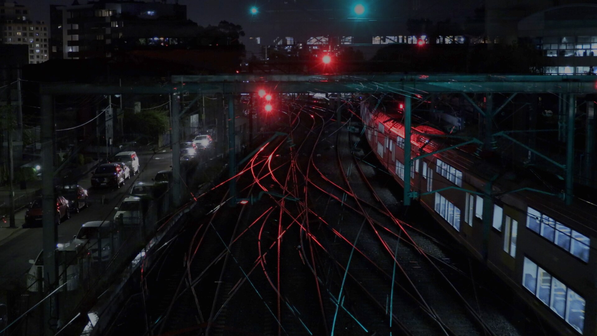 An aerial night-time photo of converging train lines and a train.