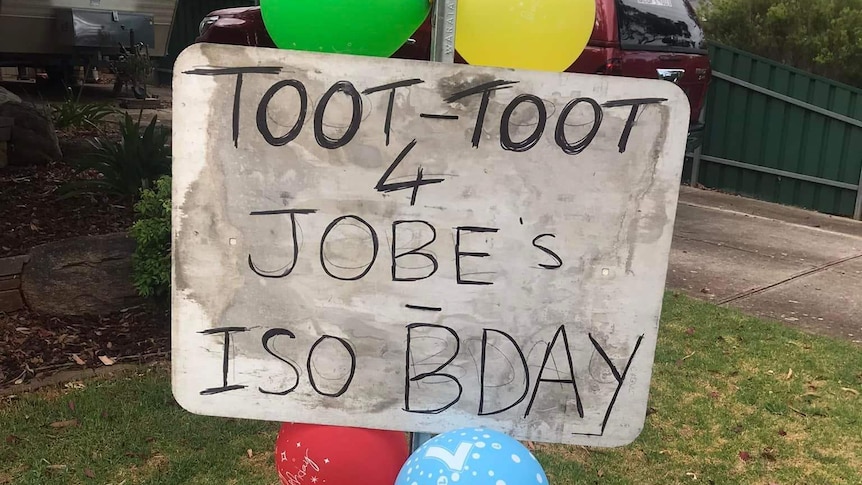 A homemade sign saying "toot toot for Jobe's iso birthday