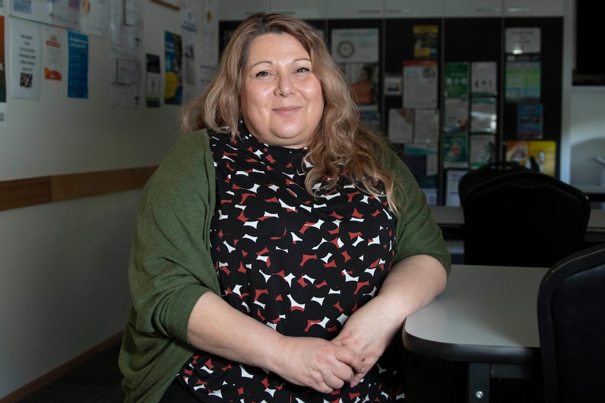 A woman sits on a seat and smiles.