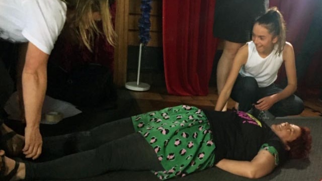 A woman lies on the ground while two others try to move her at a workshop on non-violent protest techniques.