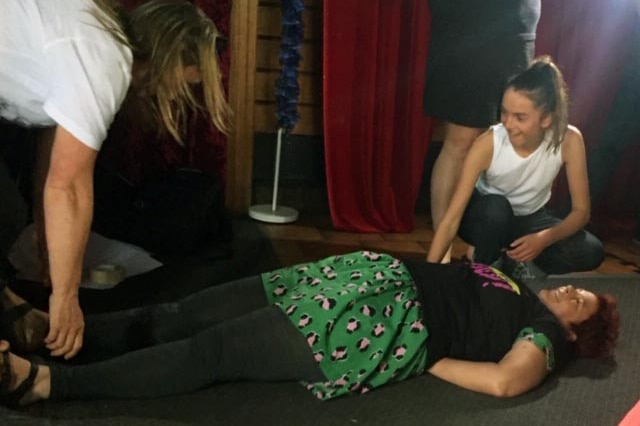 A woman lies on the ground while two others try to move her at a workshop on non-violent protest techniques.
