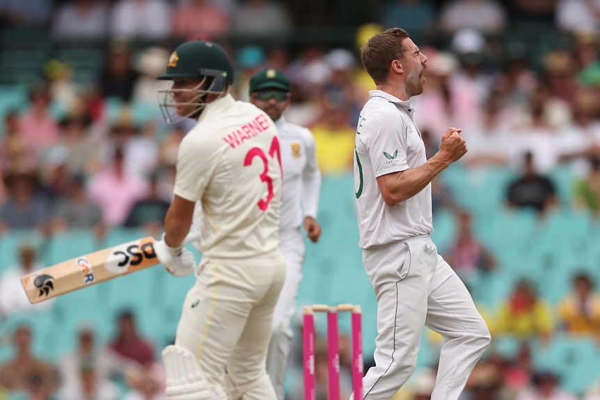 Anrich Nortje runs and celebrates as David Warner looks off to one side in the foreground