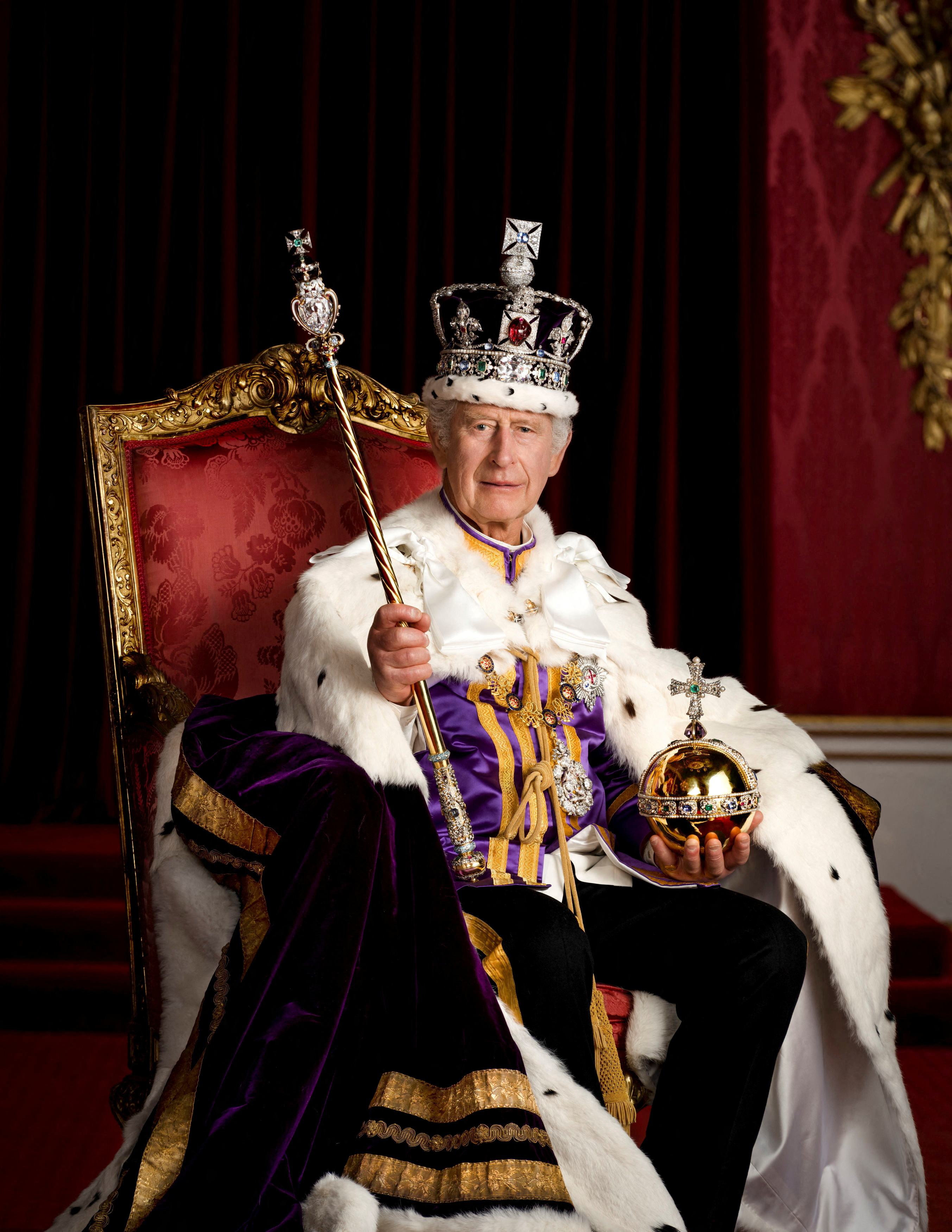 King Charles sits on a throne, in a crown holding an orb and sceptre.