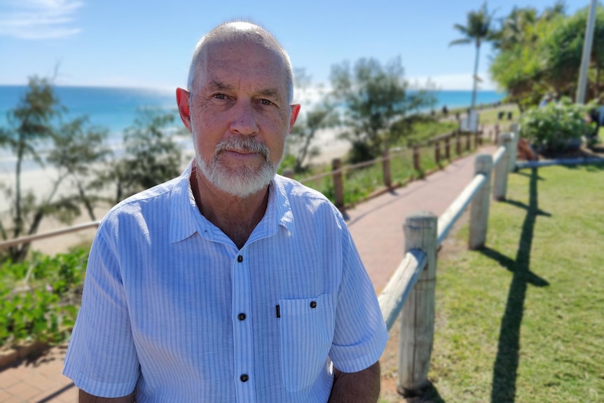 Chris Mitchell standing in footpath in front of beach