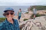 A woman stands near a cliff overlooking the sea, with friends in the background for a story on going off the contraceptive pill.
