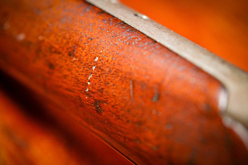 A close up of damaged wood on a gun.