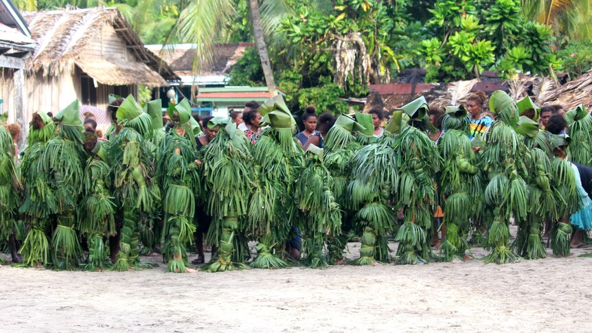 Woman in a line waiting, wearing banana leaves. 