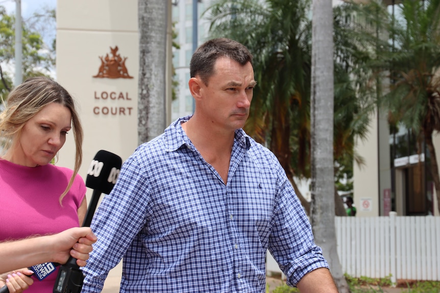 a brunette man wearing a collared shirt looking stern