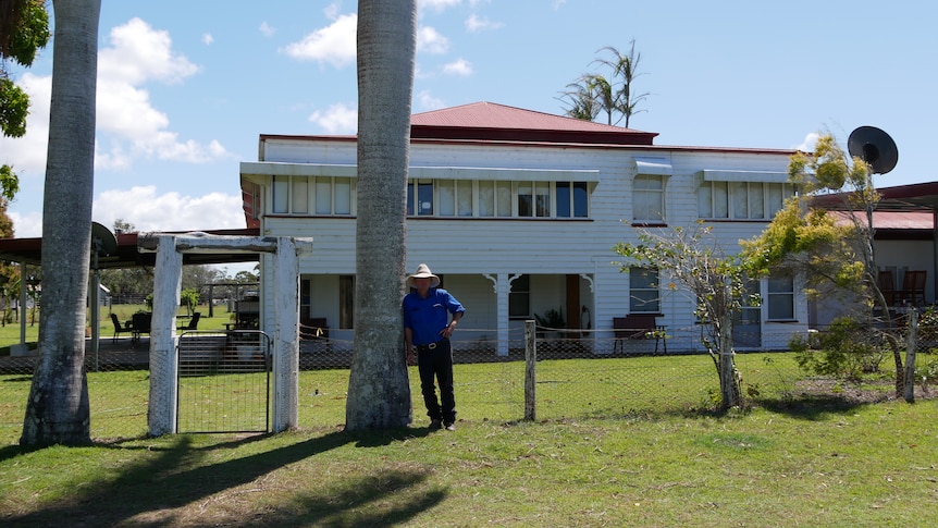 A man standing outside a rural homestead