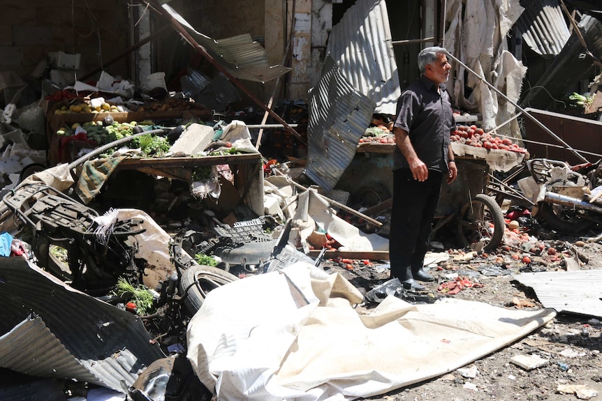 A Syrian man stands amid ruins after an air strike on a market.