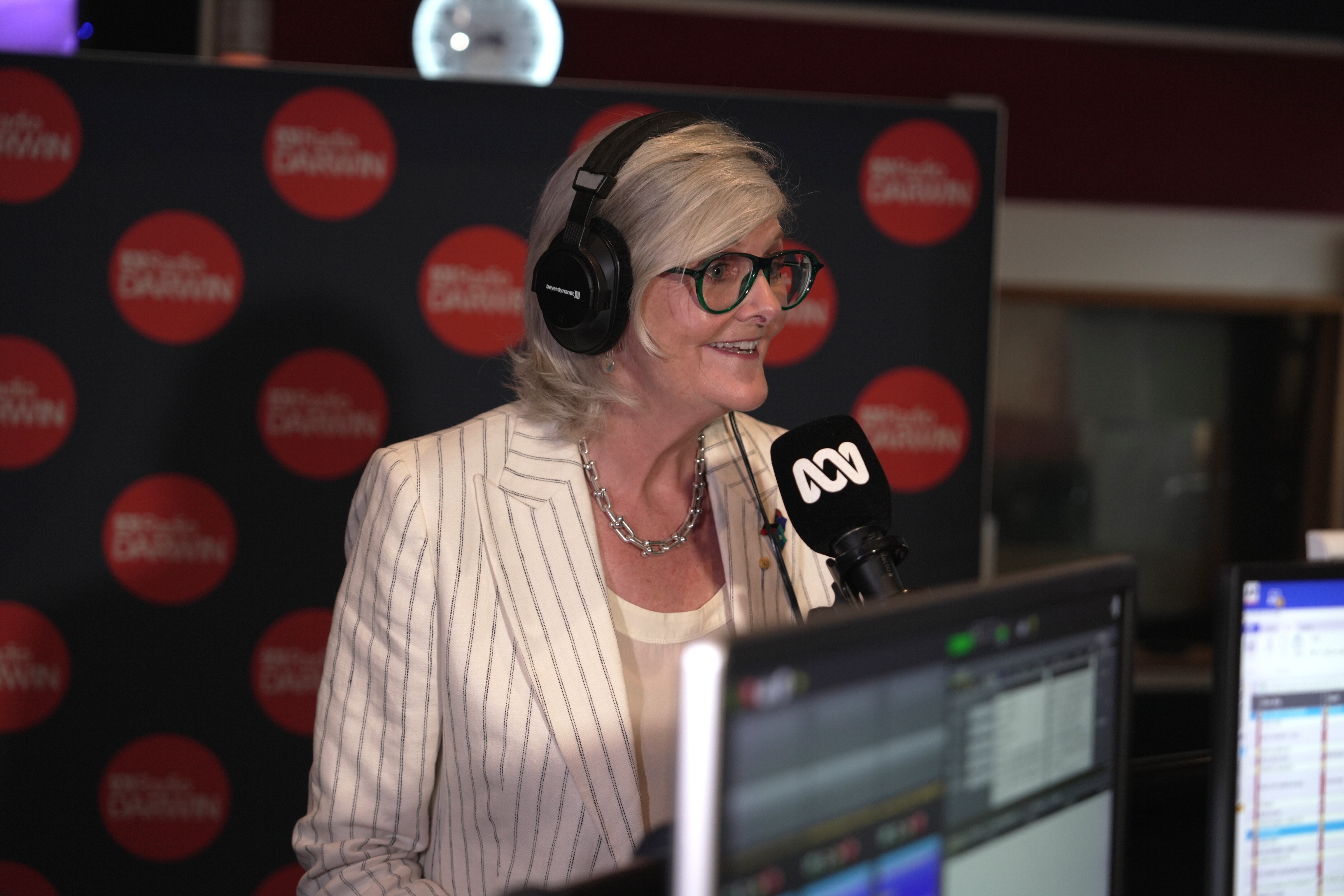 A woman speaks into a microphone in a radio studio
