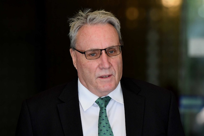 A man wearing a suit with a green tie