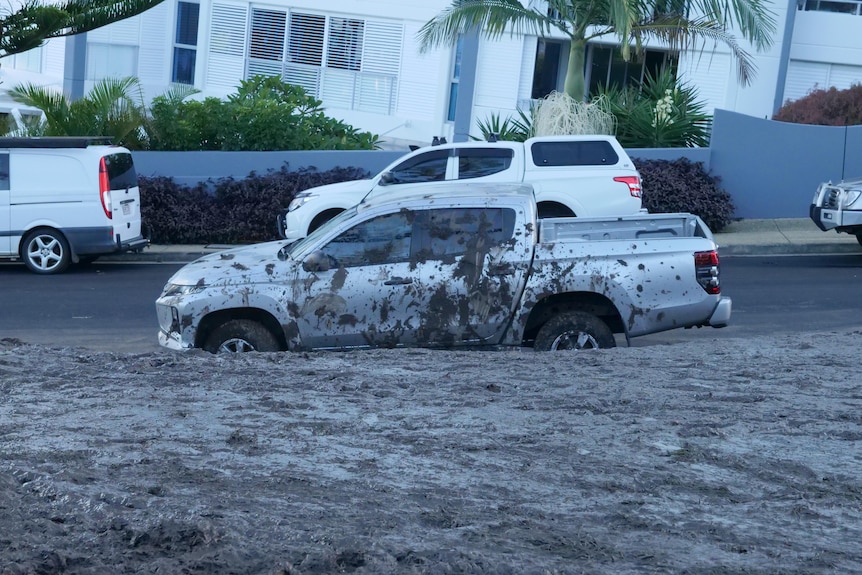 A ute at the foot of a hill, splattered with mud.