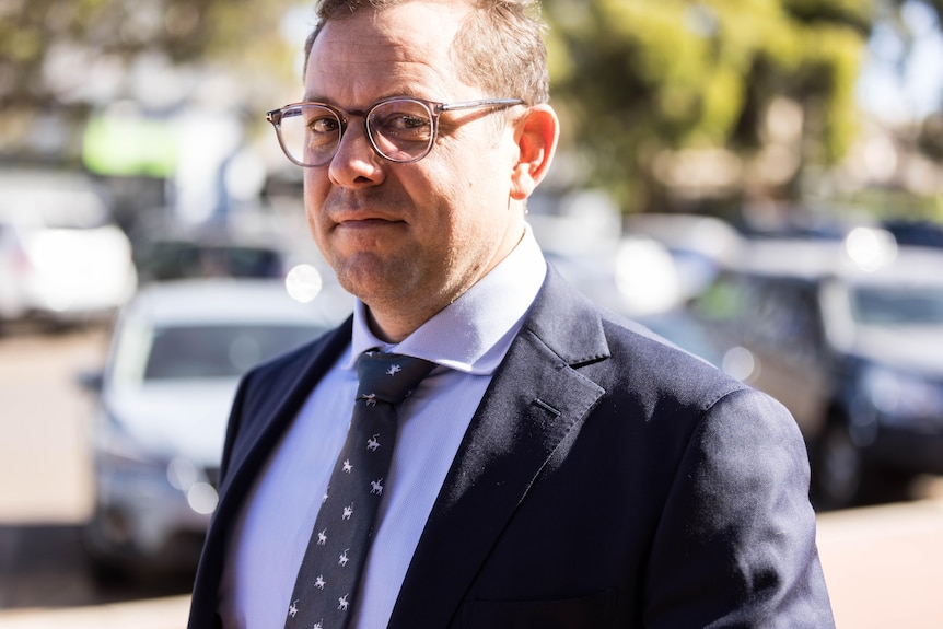 A man in a suit walking into court trial.  