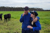 Jess and Cody Shilling stand on their pasture with some black cattle.