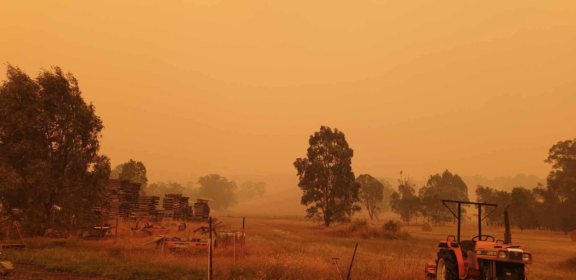 Névoa vermelha e fumaça vistas de uma propriedade rural.