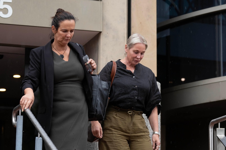 A blonde woman and a dark-haired woman both leave the court building in Hobart.
