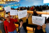 People hold signs with the names of people detained and denied entry at LAX