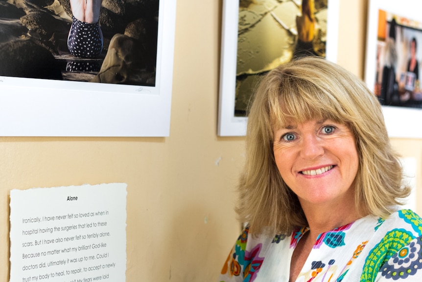 A woman standing in front of a series of photographs hanging on the wall.