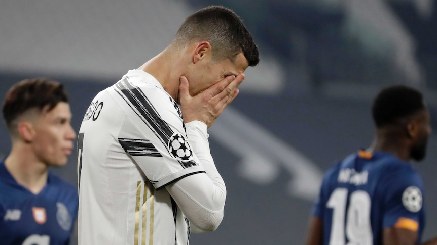 A Juventus footballer holds his head in his hands during a Champions League match.