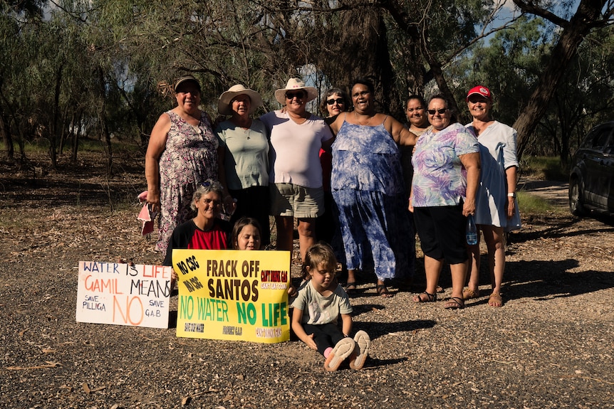 A group of women with some children standing with protest signs at their feet.