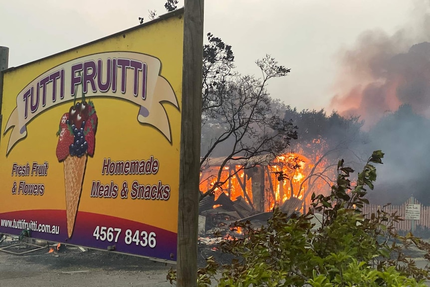 a building burning behind colourful signage