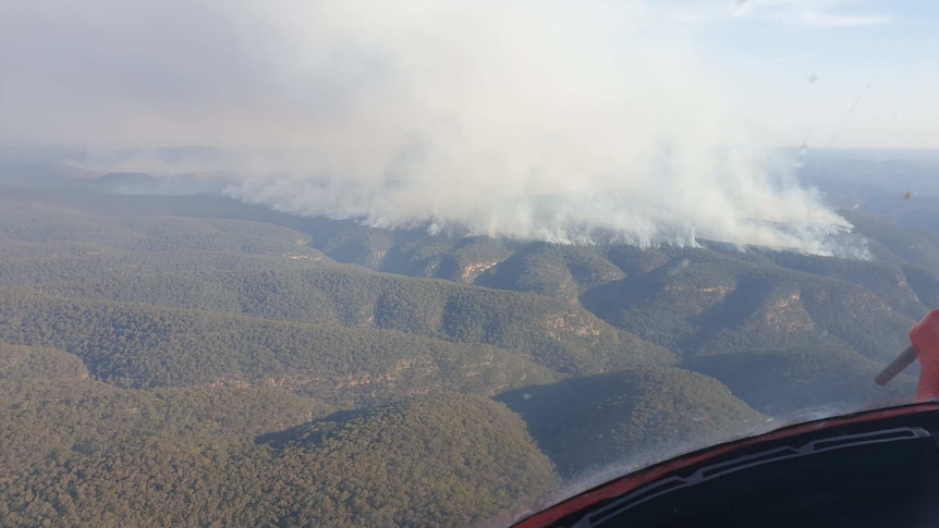 A large amount of smoke rising from a hill, viewed from a plane