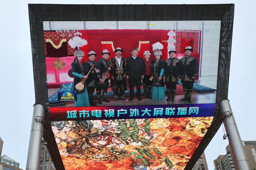 A giant screen shows news footage of Chinese President Xi Jinping visiting Xinjiang Uyghur Autonomous Region