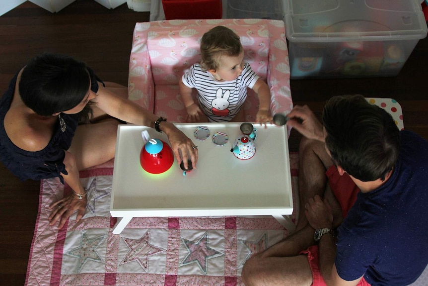 An aerial view of Johnny, Bethan and Aviana McElwee playing with a plastic tea set in their living room.