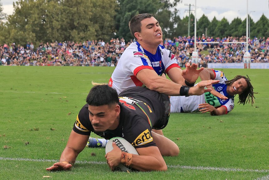A rugby league player dives over to score in the corner 
