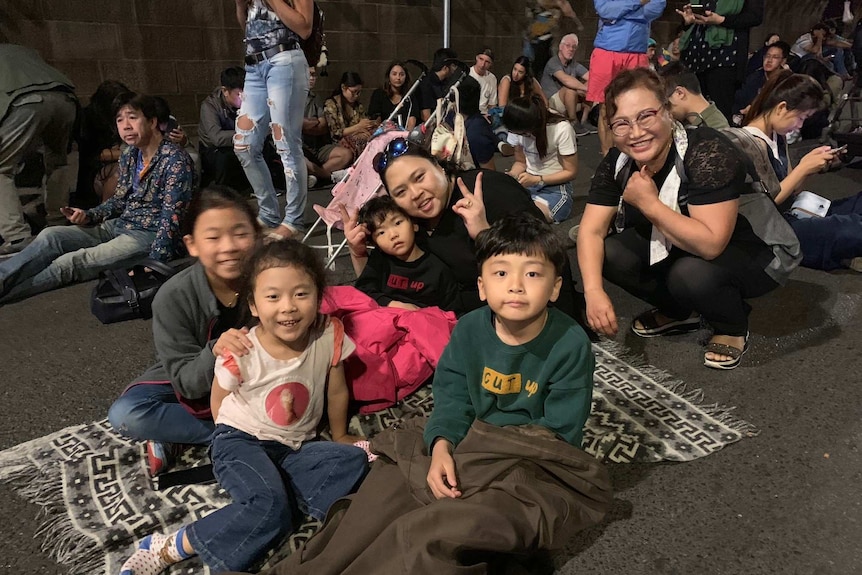 A crowd of people sit on the crowd and one family smiles for a photo