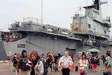 Foreign tourists disembark from a Thai Navy aircraft carrier at Sattahip naval base