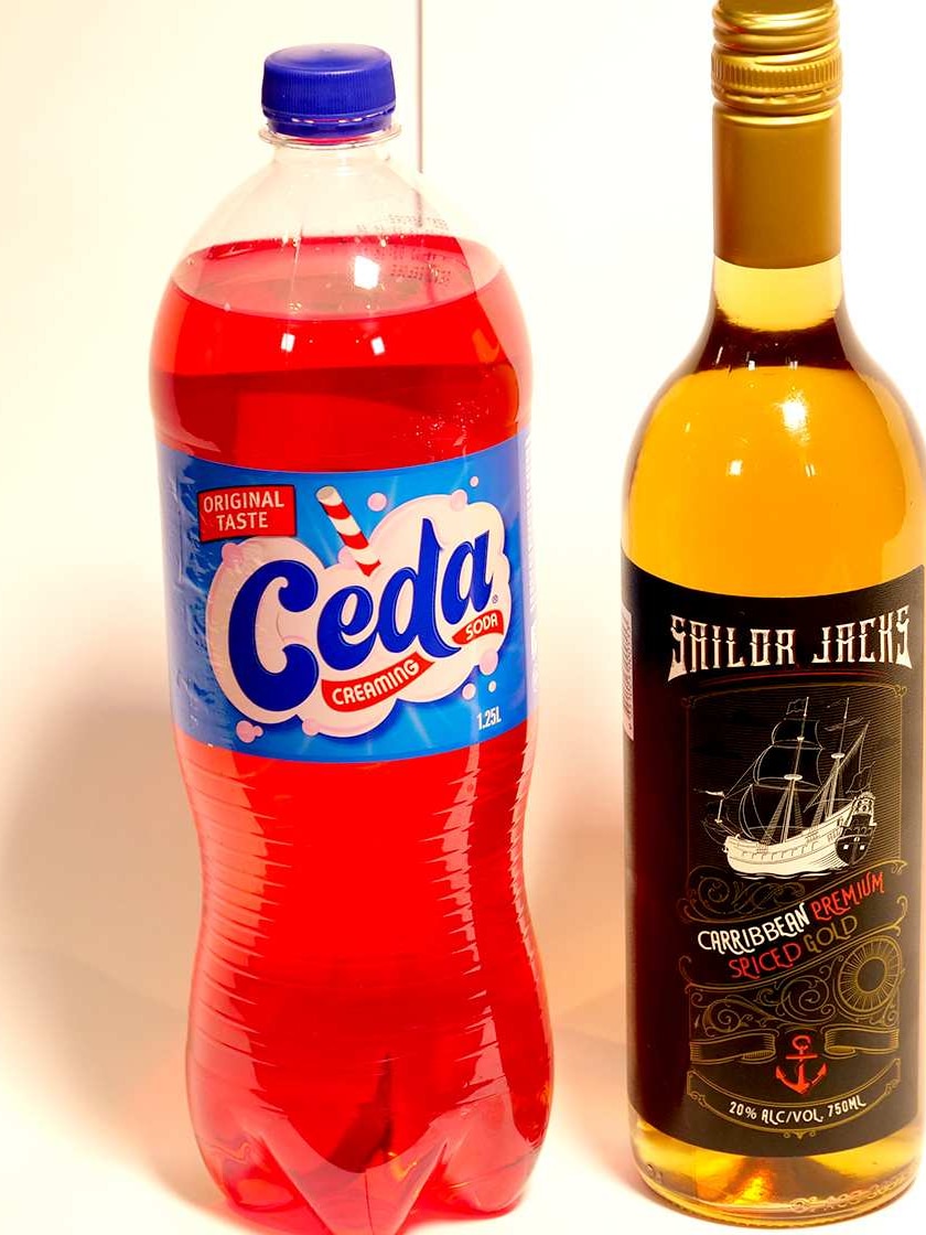 A bottle of soft drink and a bottle of brown liquid