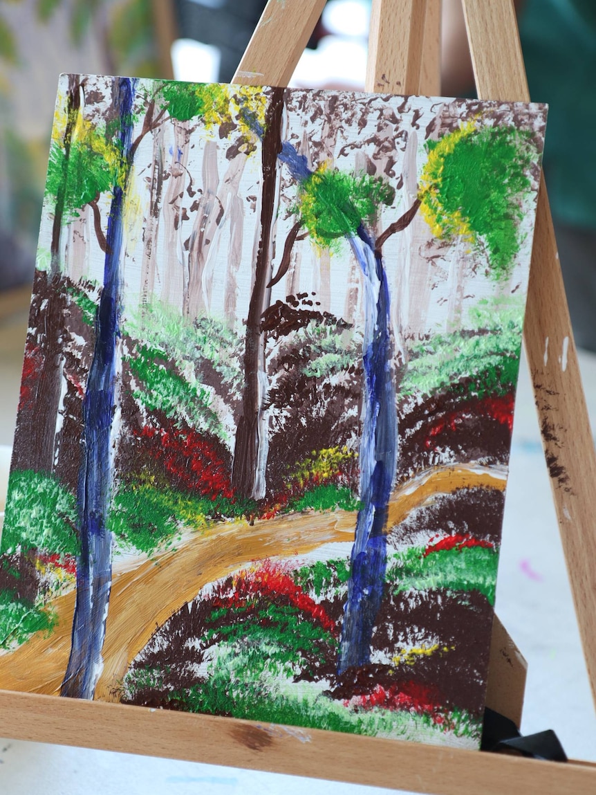 A painting of a forest sits on an easel.