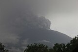Ash and smoke pours out of a distant Mount Agung.