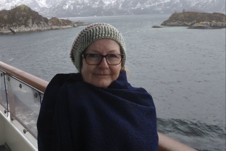 A woman in a beanie poses for a photo on a boat