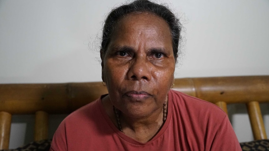 Martina Parry is wearing a red shirt and looking straight at the camera with a stern expression.