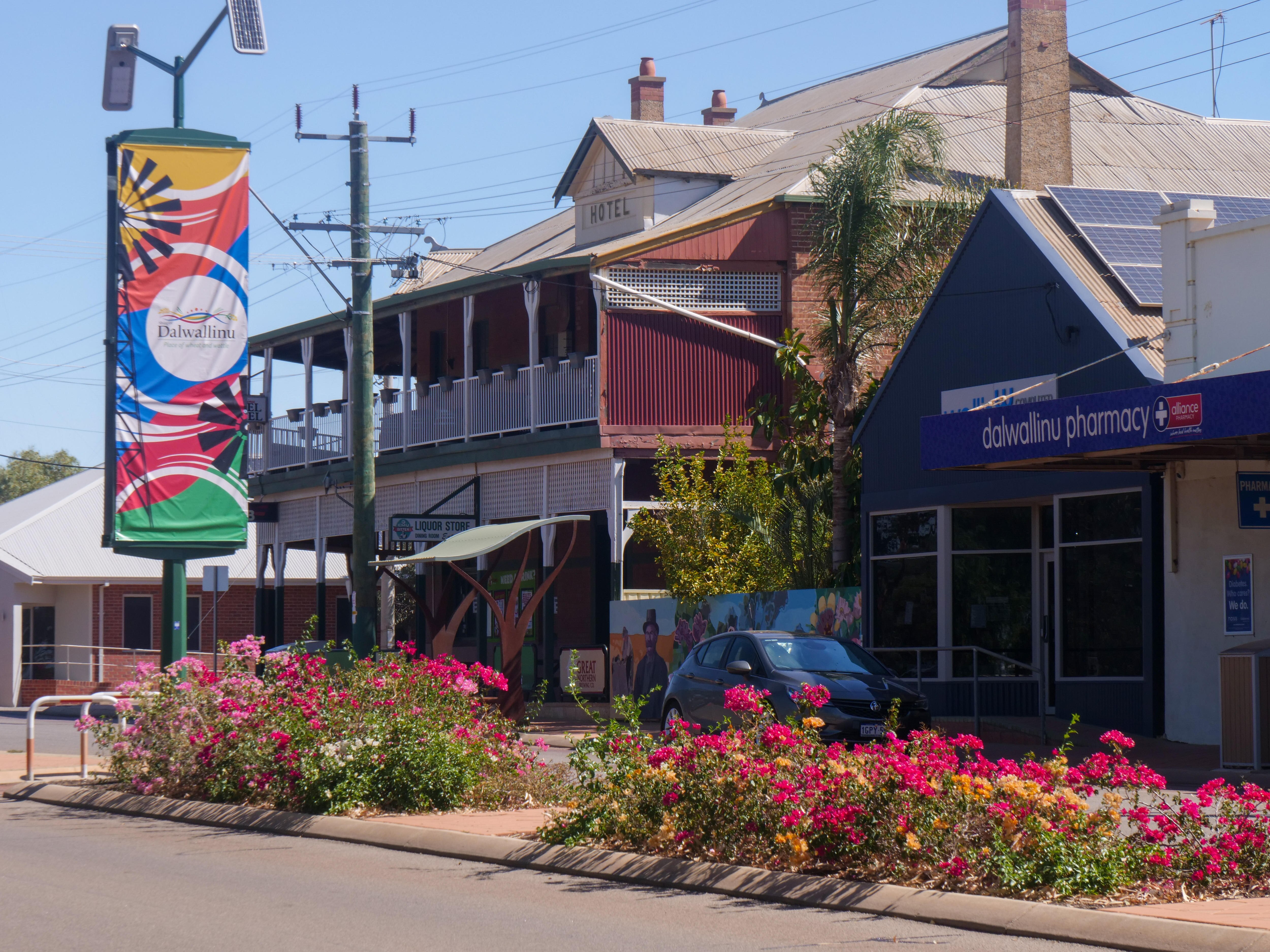 A streetscape of a country town with flowers in the middle of the road and a historic country pub.