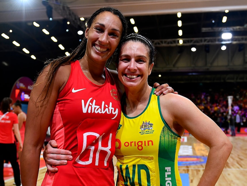 Two netballers - one English, one Australian - stand together and smile after a big match.