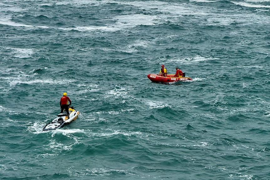 A jet ski and rubber search boat in the ocean, with rough waves and wind chop.