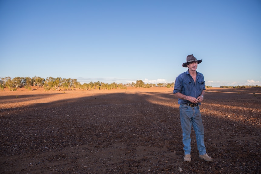 A man standing in a dry paddock.