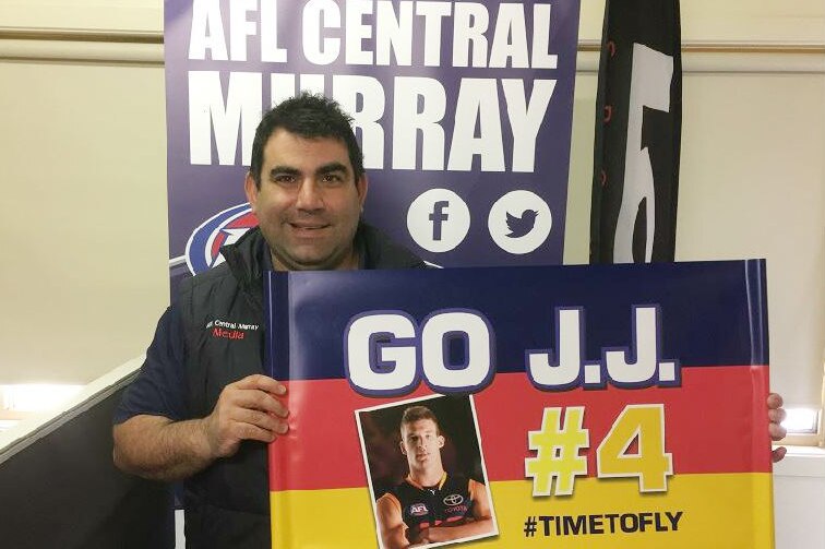 A man holds a 'go JJ' banner featuring Adelaide Crows' Josh Jenkins who is in the AFL grand final