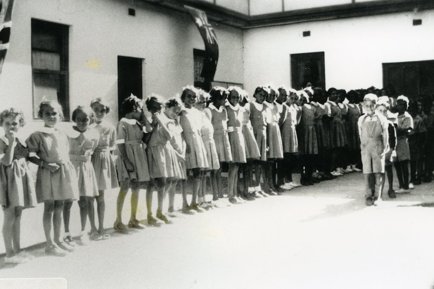 Children line up out the front of a school