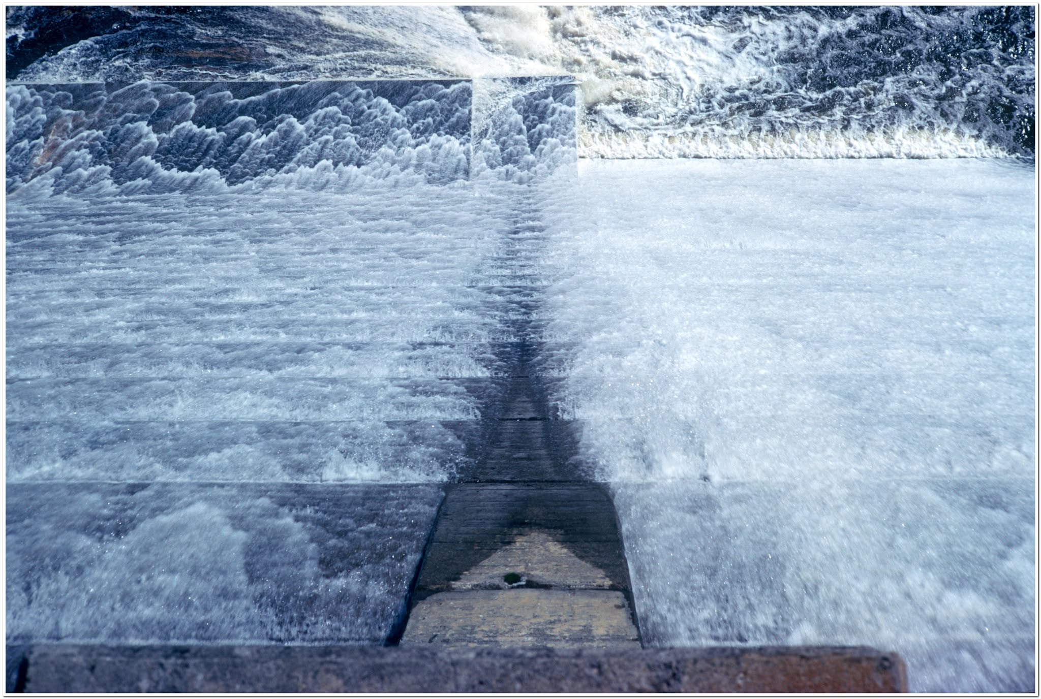 Water pouring down the dam wall during an overflow, see from above
