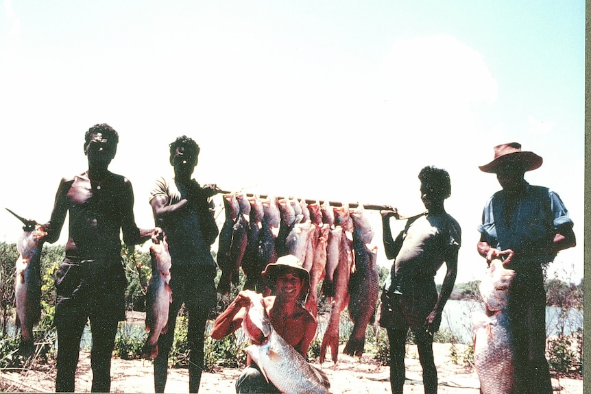 Four men carrying a rack of dead fish