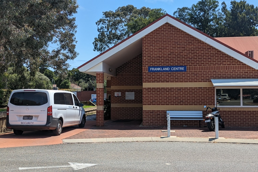 The brick exterior of the Frankland Center with a truck labeled "Guard" parked outside.